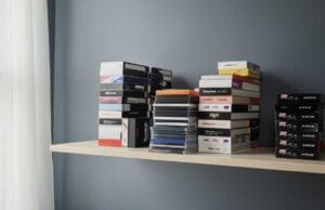 How to Store VHS Tapes How to store vhs tapes — a row of VHS cassettes stored upright on a shelf in a cool, dry room.